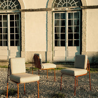 Striped beige and cream chairs with rust-colored metal frames, set against a backdrop of historic doors.
