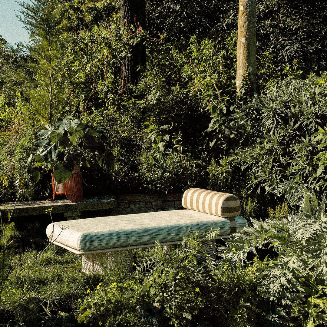 Sunshine yellow and earthy green stripes on a textured, neutral-toned outdoor lounge chair amidst lush foliage.