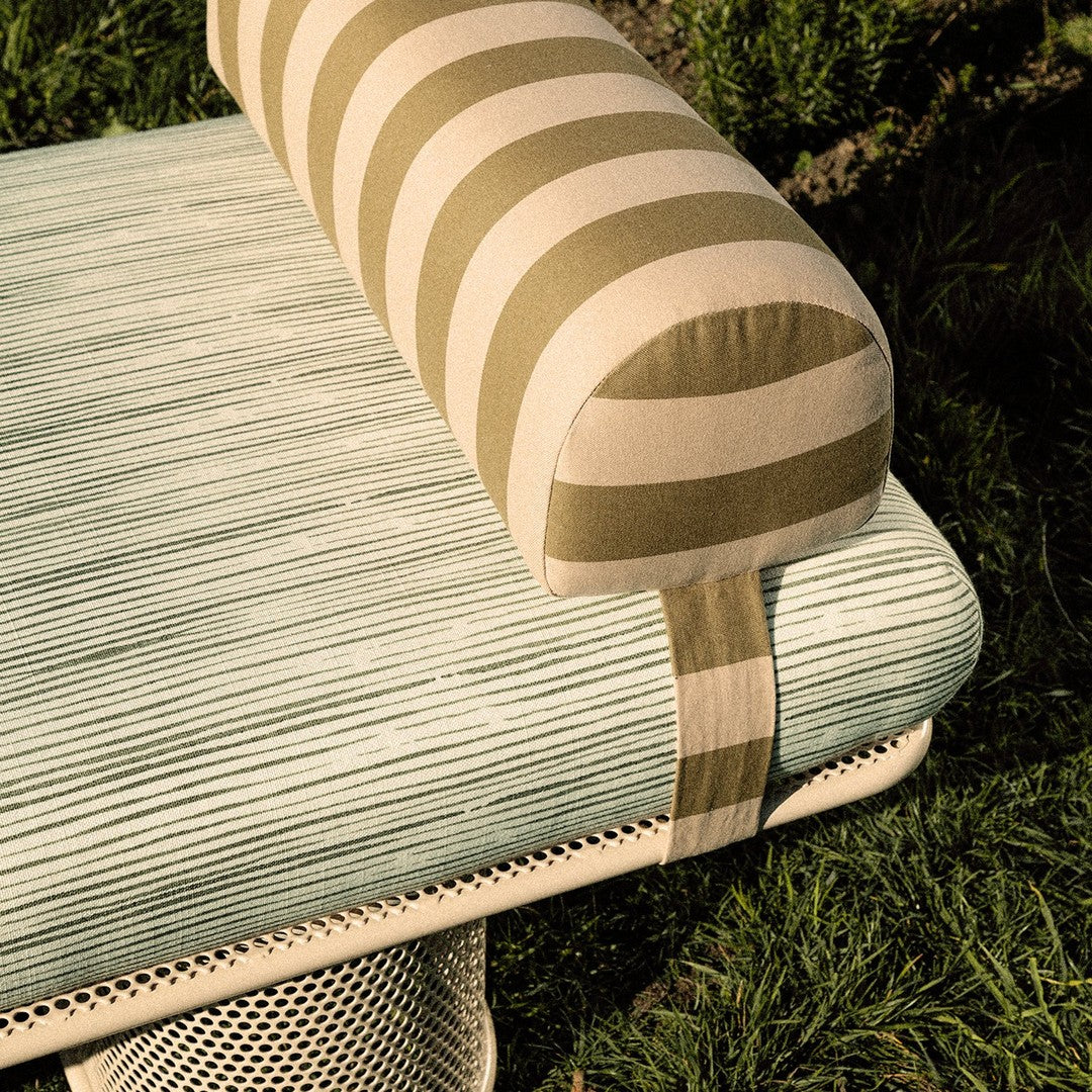 Striped olive and beige bolster cushion on a textured mint green upholstered seat. Modern outdoor furniture design.