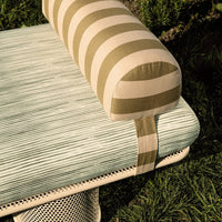 Striped olive and beige bolster cushion on a textured mint green upholstered seat. Modern outdoor furniture design.