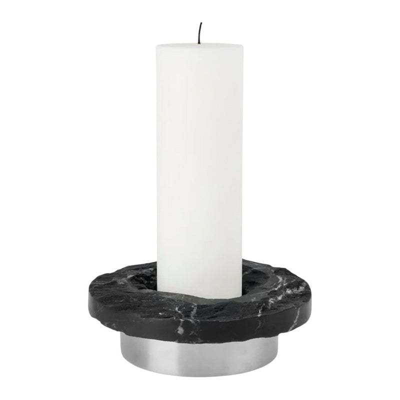 White candle on a black marble holder with silver base, featuring sleek, modern design elements.