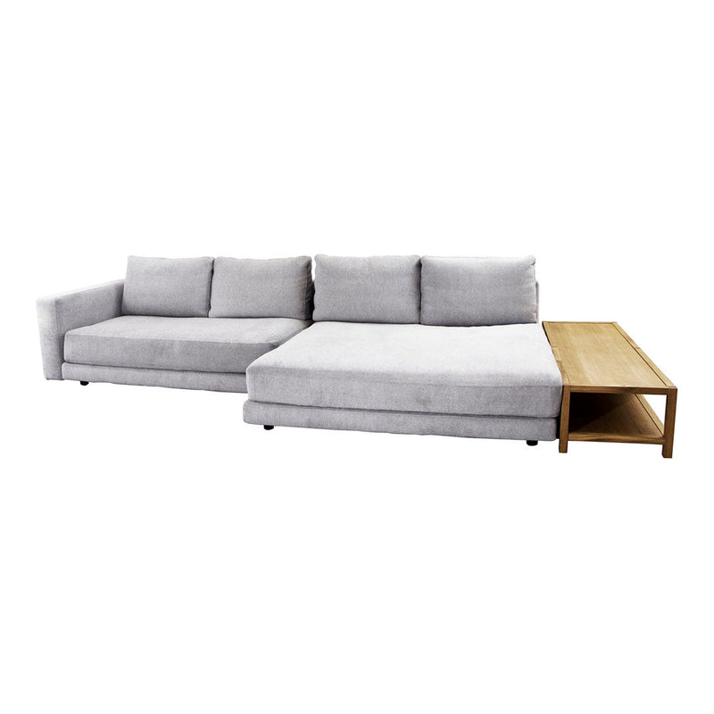 Soft grey sectional sofa with clean lines and plush cushions, featuring a minimalist wooden side table.