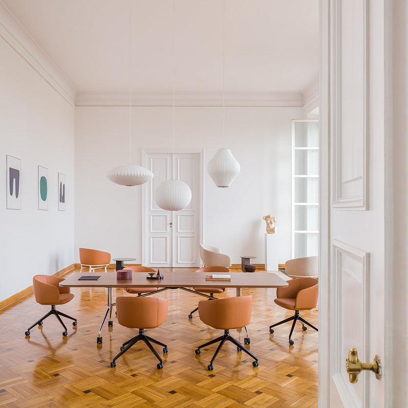 Modern office space with peach chairs, wooden flooring, and minimalist white decor. Elegant and inviting atmosphere.
