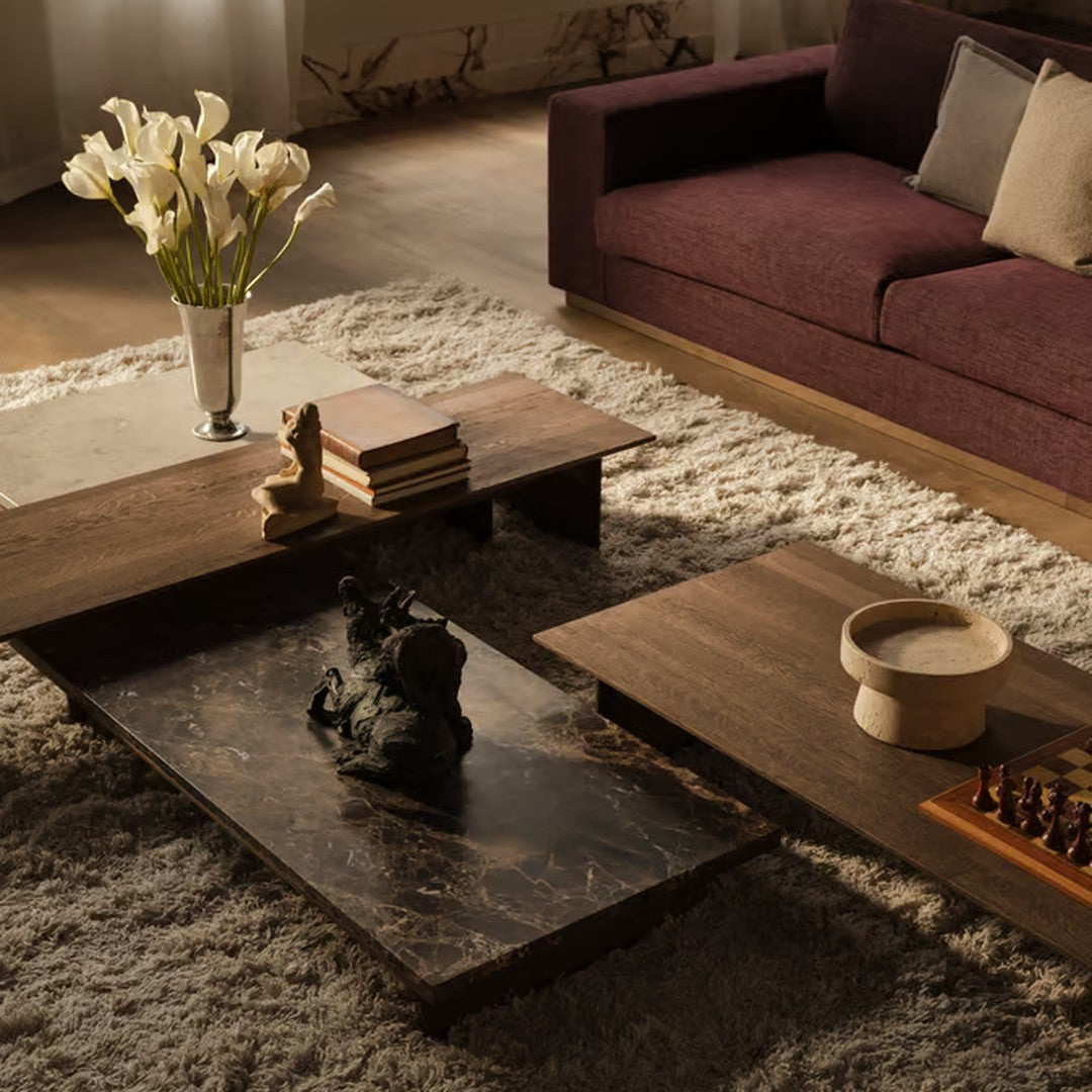 "Elegant wood coffee tables in dark brown and textured black marble, set on a light, plush area rug."