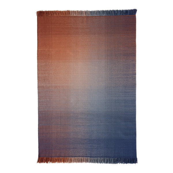 "Gradient woven blanket with warm orange to cool blue ombre, featuring soft fringed edges."