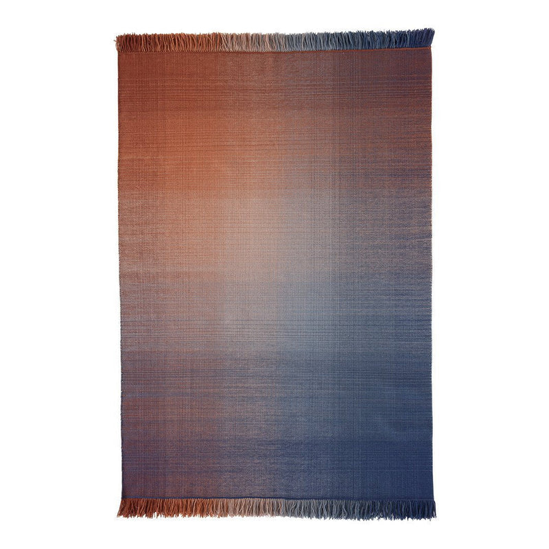 "Gradient woven blanket with warm orange to cool blue ombre, featuring soft fringed edges."