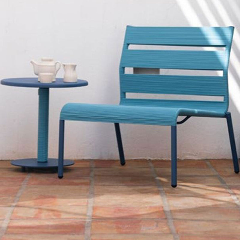 Aqua blue outdoor chair and table with sleek lines, set against a textured terracotta floor.
