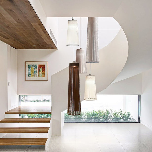 "Hanging pendant lamps in shades of white, gray, and brown enhance a modern staircase with sleek wood accents."