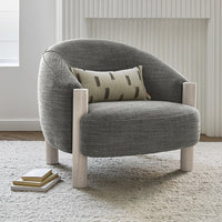 Gray upholstered armchair with a textured fabric and light wooden legs, featuring a patterned decorative pillow.