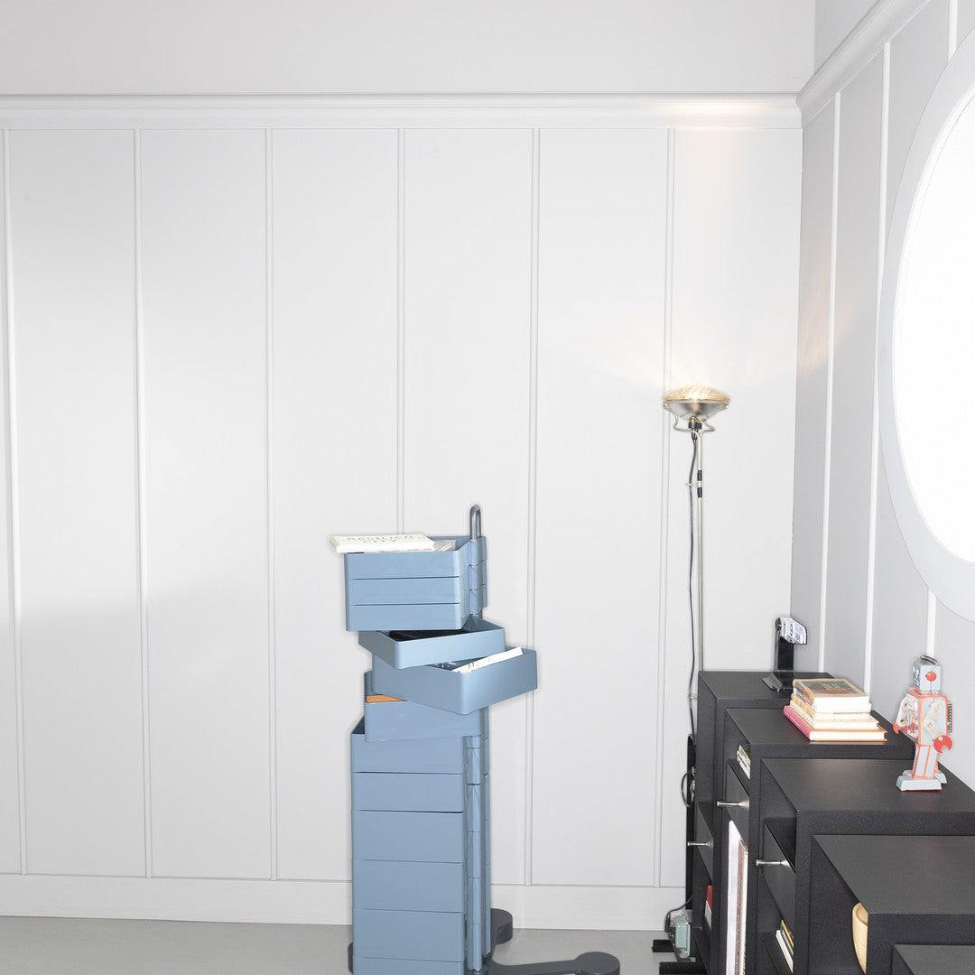 Stack of light blue storage boxes beside a black cabinet with a minimalist design on a neutral background.