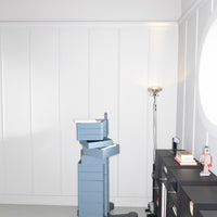 Stack of light blue storage boxes beside a black cabinet with a minimalist design on a neutral background.