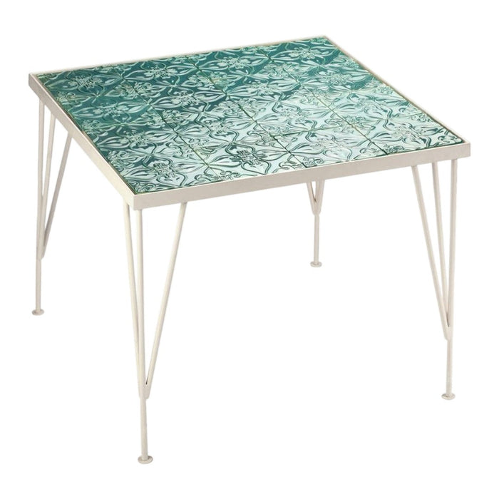 Square table with a teal and turquoise patterned tile top and white metal legs.