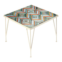 Square table with colorful geometric pattern in orange, blue, and white, complemented by metal legs.
