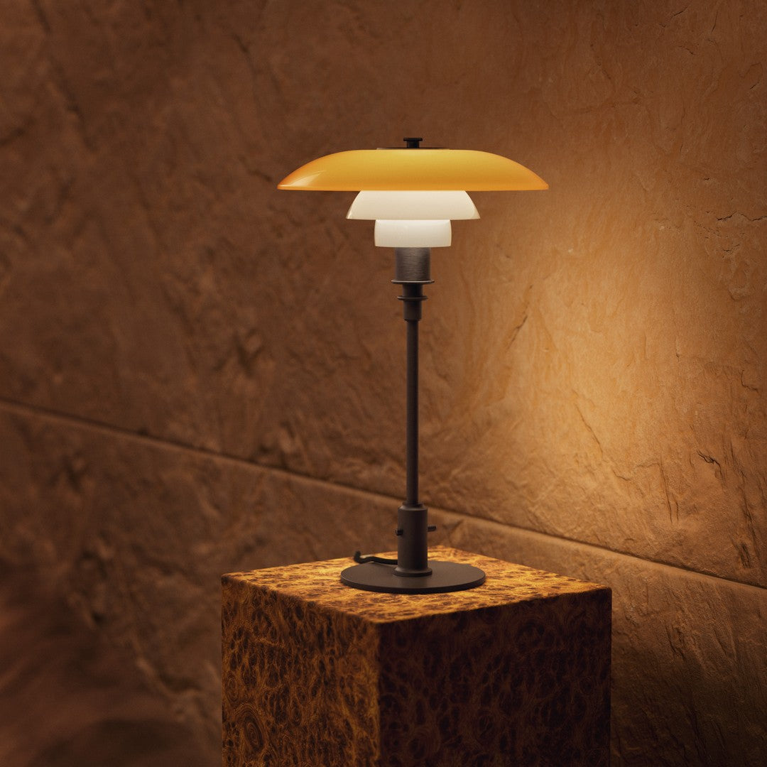 "Modern table lamp featuring a layered design with orange, white, and black elements against a warm, textured wall."