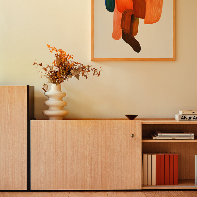 Light wood storage unit with smooth, natural finish; featuring warm neutral tones and a pop of vibrant orange in decor.