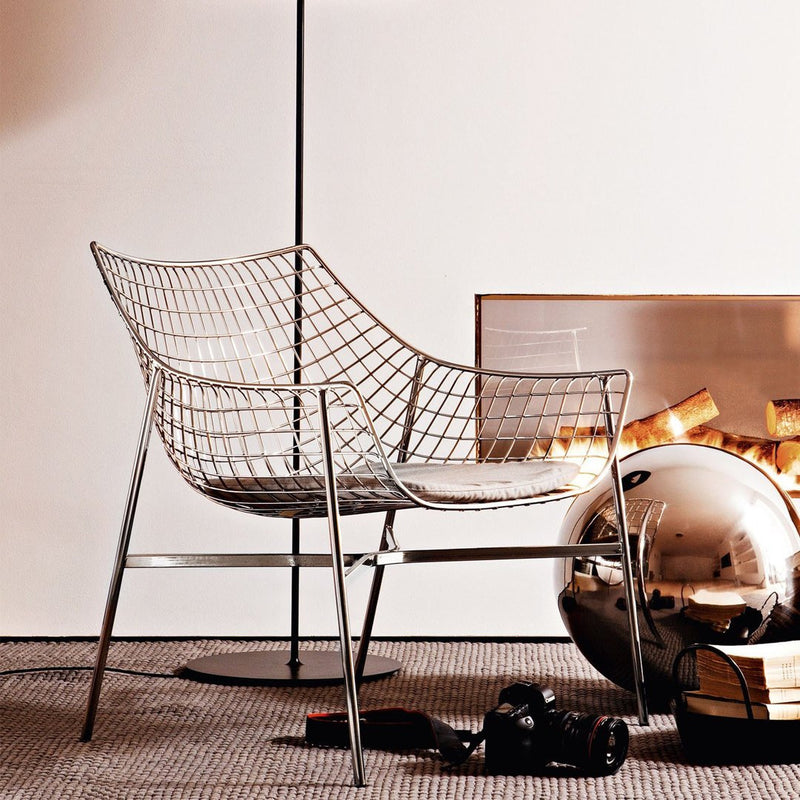 Stylish wire chair in silver with a modern geometric pattern, set against a warm, neutral-toned backdrop.