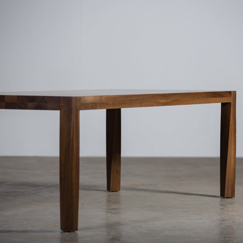Simple wooden table with a rich brown finish and smooth, solid surface on a concrete floor.