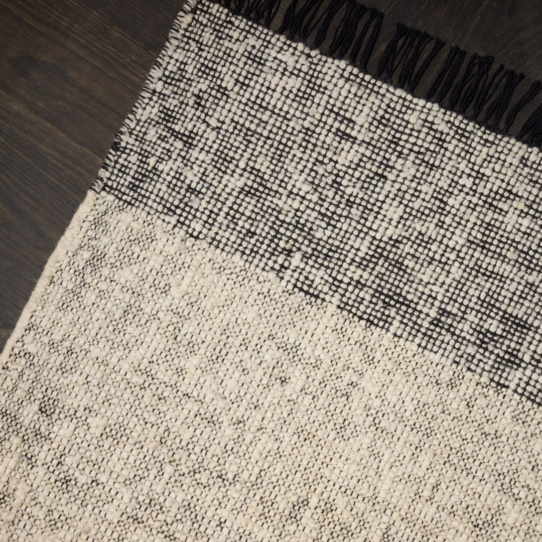Gray and black patterned rug with fringed edges, featuring a textured design and a contemporary monochrome palette.