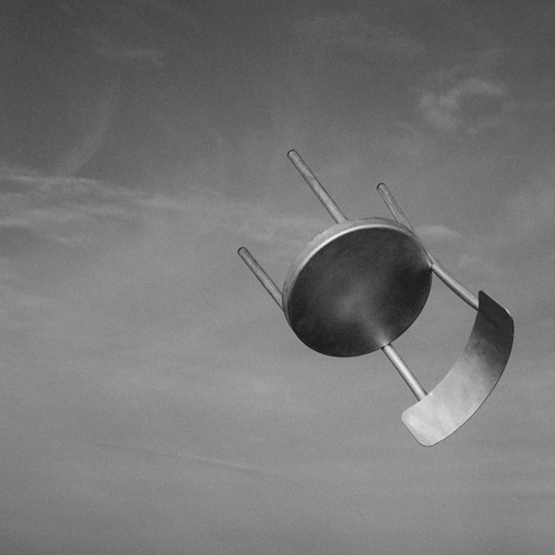 Black and white image of a flying chair with smooth, metallic finish and minimalistic design.