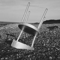 Stylish black and white modern chair with sleek stainless steel legs on a gravel surface.
