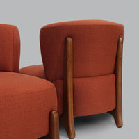 Rust-orange upholstered chair with smooth wooden legs, showcasing a modern, minimalist design.