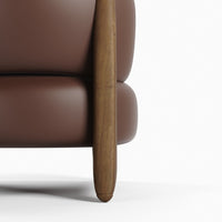 Brown leather sofa with smooth texture and natural wood legs, showcasing a modern and minimalist design.