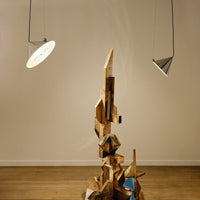 Abstract wood sculpture featuring a mix of natural tones and geometric patterns, complemented by minimalistic lighting.