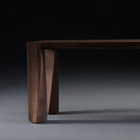 Dark walnut wood table with a smooth finish and unique, angled leg design against a gradient gray background.