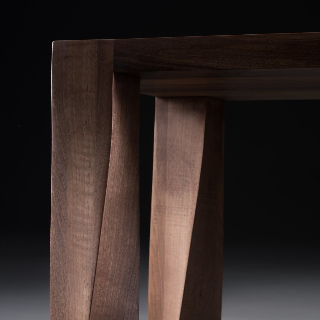 "Dark walnut wood table legs featuring unique, textured patterns and smooth finishes."