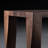 Wooden table leg in rich walnut finish with smooth matte texture and geometric cutout design.