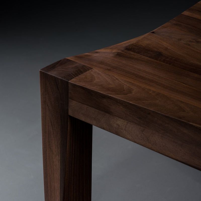 Wooden table with rich walnut finish and smooth, angular edges showcasing natural grain patterns.