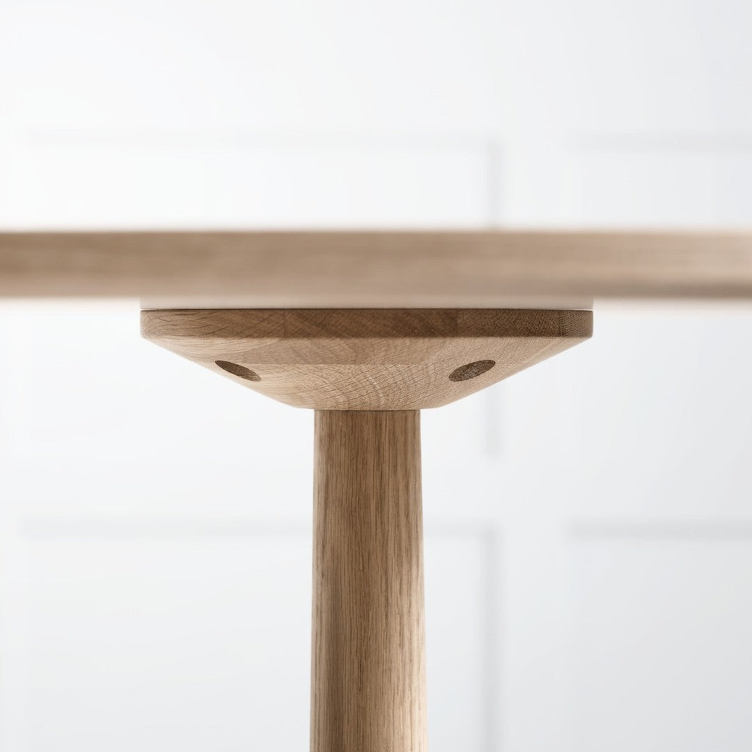 Light natural wood table leg with a smooth grain pattern against a soft white background.
