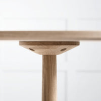Light natural wood table leg with a smooth grain pattern against a soft white background.