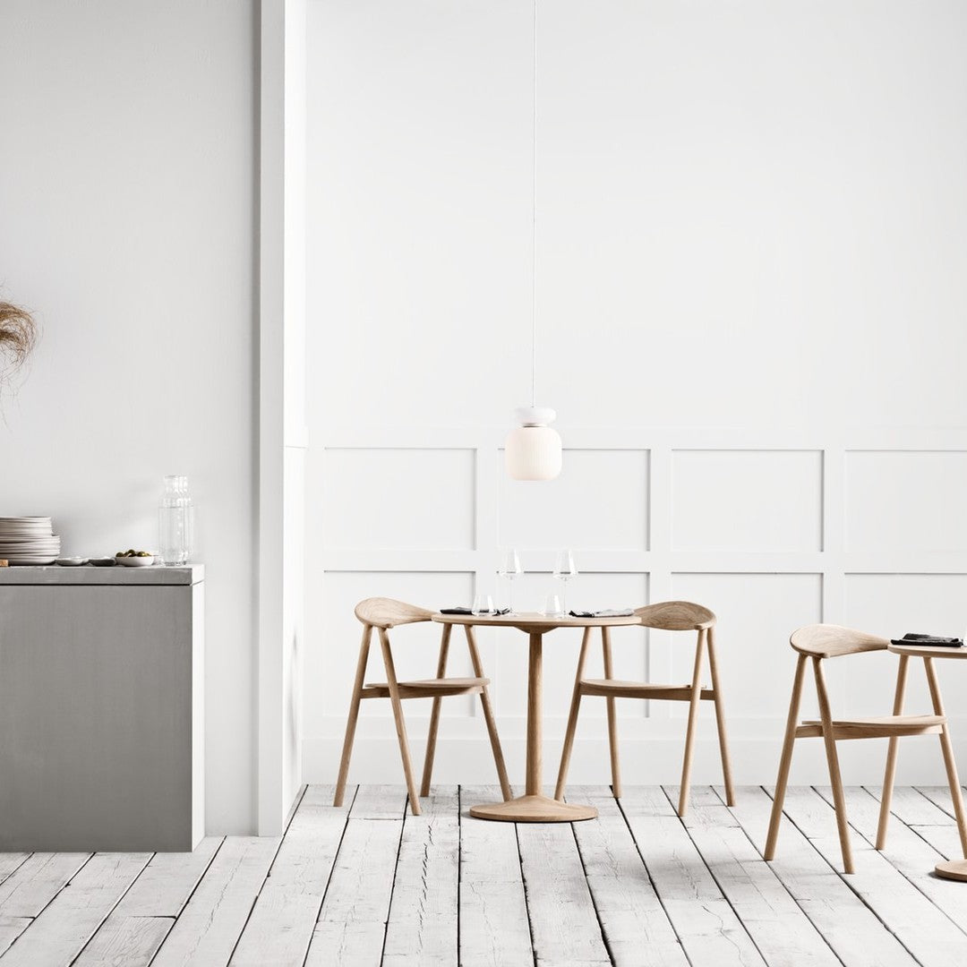 Minimalist white walls, light wood furniture, and soft neutral tones create a serene dining atmosphere.
