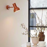 Terra-cotta wall lamp, neutral ceramic vases, and fresh green branches against a light backdrop. Elegant, modern decor.