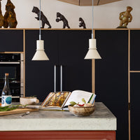 Modern kitchen scene featuring black cabinetry, white pendant lights, concrete countertop, and earthy-toned accents.