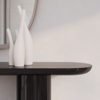 White minimalist vases on a sleek black tabletop, featuring smooth lines and modern design.