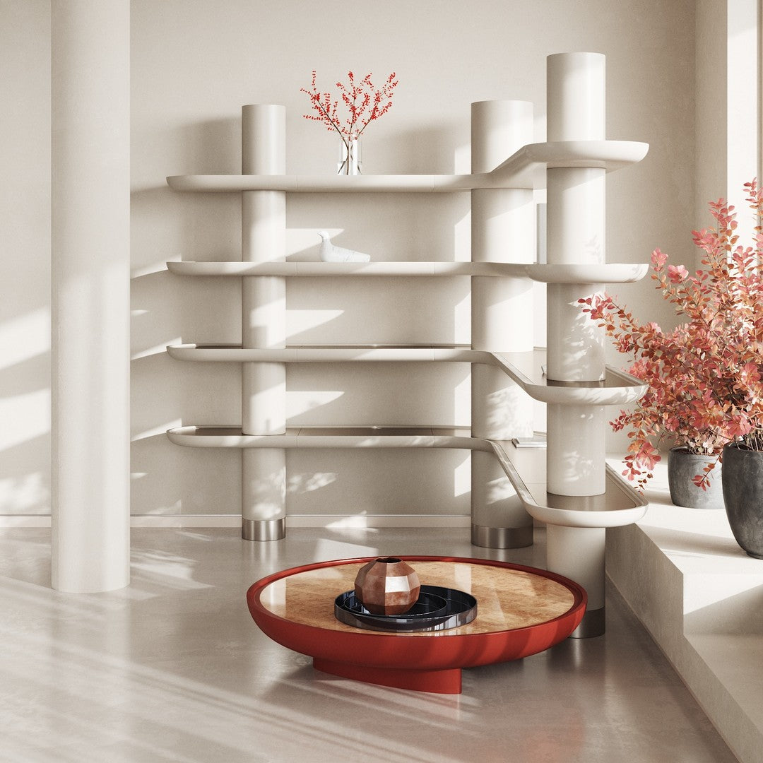 Modern white shelving unit with smooth lines, featuring a round red coffee table and vibrant pink floral accents.