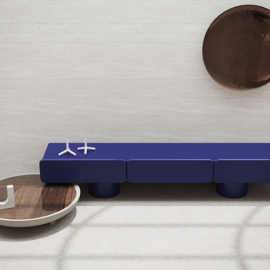 Modern navy blue bench with sleek lines, complemented by a round wooden tray and decorative wall elements.