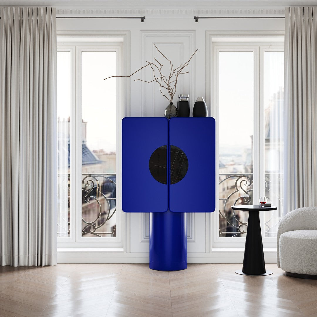 Bold blue cabinet with a round black pattern, set against bright natural light and elegant neutral tones.