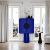 Bold blue cabinet with a round black pattern, set against bright natural light and elegant neutral tones.