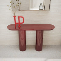 Modern burgundy console table with glossy finish, featuring a sleek oval top and rounded pillars.