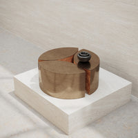 Bronze and wood geometric decor with a smooth finish, set on a light-colored stone pedestal.