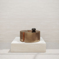 Brushed gold circular decor with black accent on a light stone base, showcasing modern minimalist design.