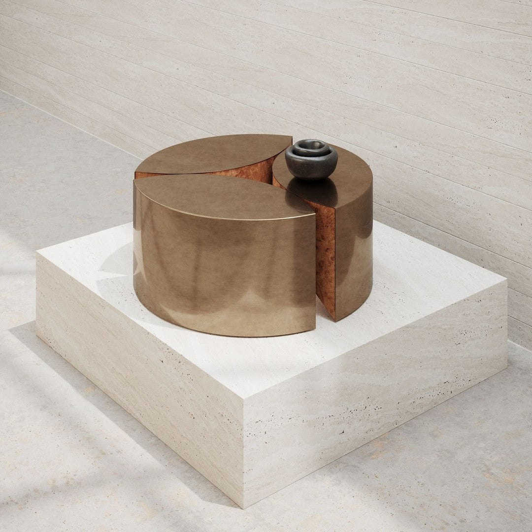 Round bronze sculpture with smooth, shiny finish, featuring a contrasting texture and shape against a light stone base.
