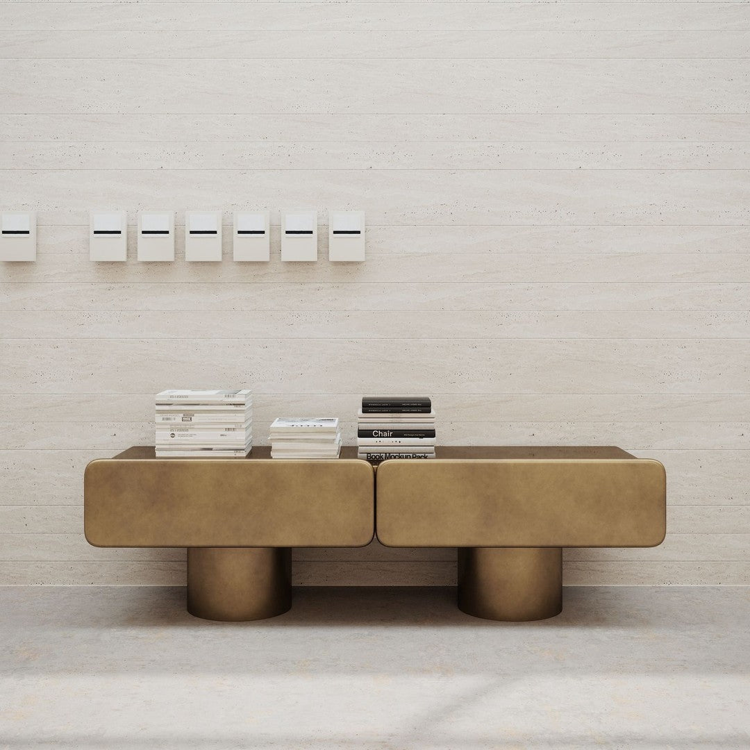 Sleek gold coffee table with a smooth surface and rounded legs, complemented by a minimalist backdrop and stacked books.