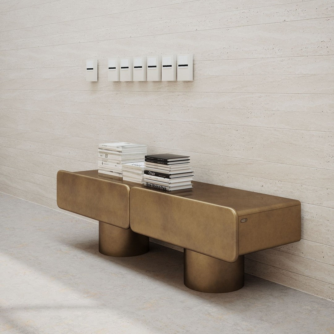Stylish brass bench with a sleek design, featuring a smooth finish and cylindrical legs, set against a neutral background.
