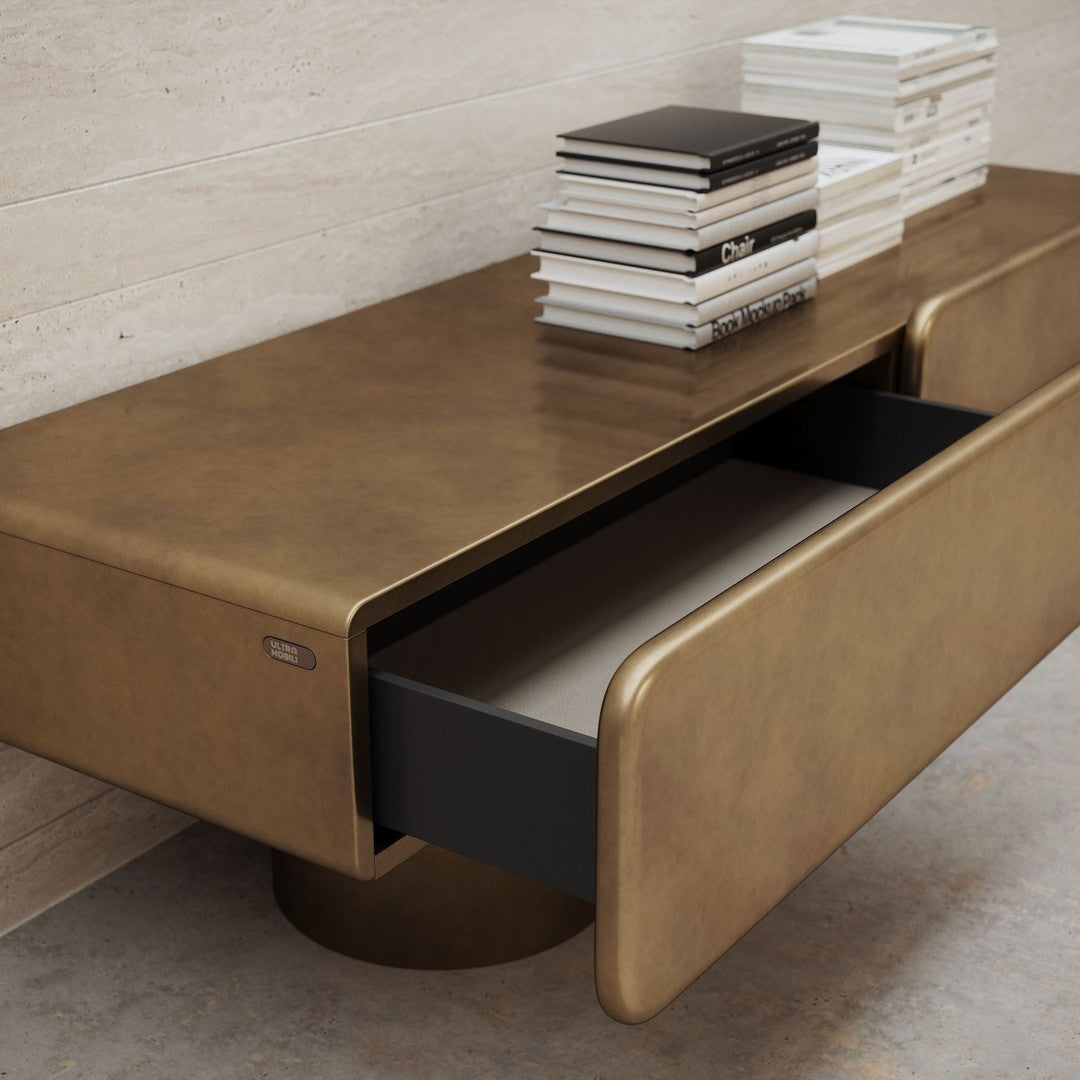 Gold-toned modern coffee table with sleek lines and a contrasting black drawer, perfect for stylish interiors.