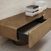 Gold-toned modern coffee table with sleek lines and a contrasting black drawer, perfect for stylish interiors.