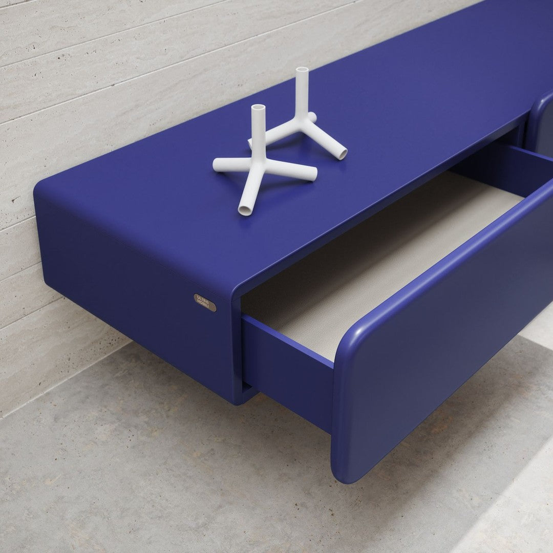Sleek purple storage cabinet with clean lines and a minimalist design, featuring an open drawer and geometric white decor.
